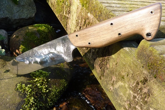 Couteau de camp semi brut de forge avec lame de 170 mm en acier homogène XC75 . Manche en zébrano, laiton et intercalaires rouges